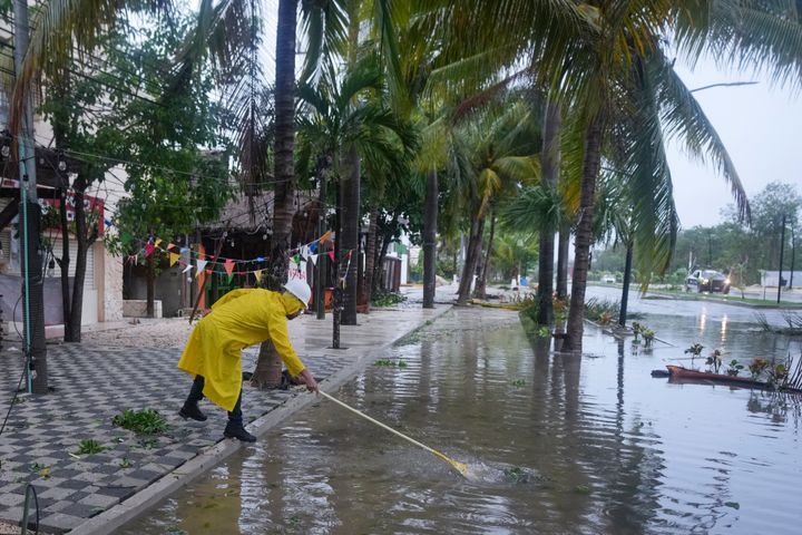 A man unclogs a drain in the aftermath of Hurricane Beryl, in Tulum, Mexico, Friday, July 5, 2024. (AP Photo/Fernando Llano)