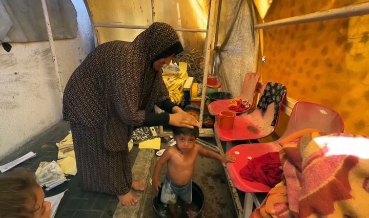 This image from video shows a woman bathing her child Friday, July 5, 2024 in Gaza City, Gaza Strip. Yarmouk Sports Stadium, one of the territory’s largest soccer arenas, is now sheltering thousands of displaced Palestinians who are scraping by with little food or water. (AP Photo)