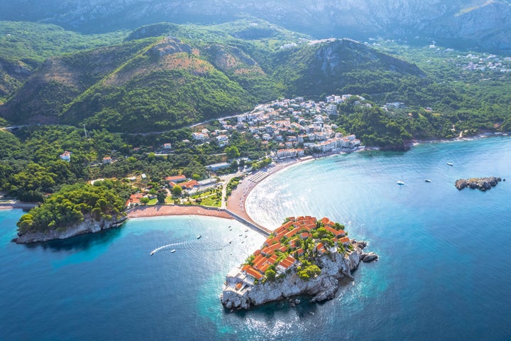 An aerial view of Sveti Stefan ("Saint Stephen"), a fortified island village on the Adriatic coast of Montenegro, connected to the mainland by a narrow causeway. 